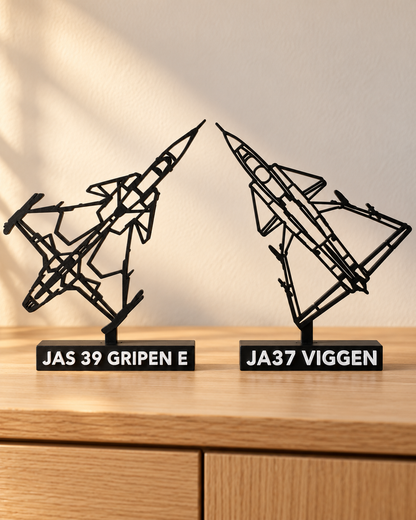 Närbild av Gripen E och JA37 Viggen med svarta silhuetter och vita modellnamn på socklarna